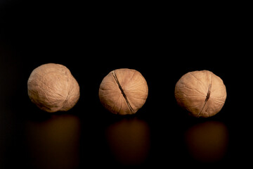 Three walnuts at a distance from each other on a black background