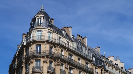 Immobilier ancien à Paris, architecture de la façade d'un immeuble d’angle haussmannien avec balcon (France)