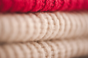 Fototapeta na wymiar Stack of bright color knitted clothes on shelf in store close up. Warm and cozy colorful sweaters. Hygge home cloth. Organized textile folded in pile.