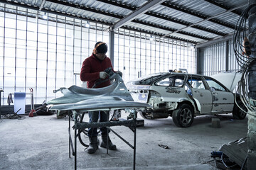 Car service worker repairs restores car