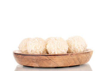 Fototapeta na wymiar A few sweet coconut candies on a wooden saucer, macro, isolated on a white background.