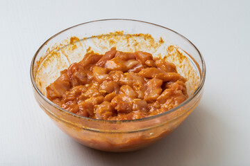 Raw chicken breasts are cut into small pieces. Pickled and seasoned with spices, placed in a glass bowl.