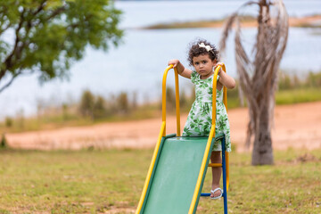 little girl in a dress plays with her mother on the playground