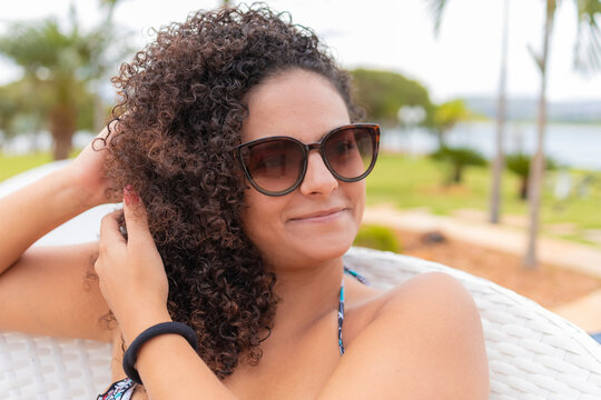 afrodescendant girl in sunglasses smiling at camera, blurred background