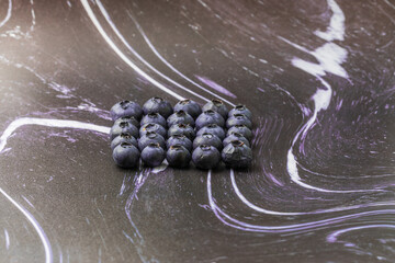 Fototapeta premium Blue-purple blueberries on a black-white background. Blueberry still life.