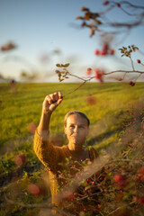 Pretty, young woman collecting rosehip fruit in autumn nature