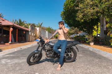 Fototapeta premium Young shirtless caucasian man with full-arm tattoo sitting on motorcycle
