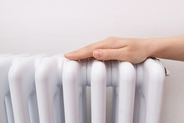Woman warms up hands over heater. Concept of the need for good central heating. Girl warms the...