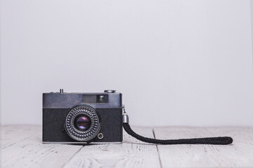 Old retro camera with a hand strap on a wooden table