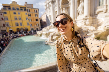 Woman visiting famous di Trevi fountain in Rome. Traveling Italy on a summer day concept. Portrait...