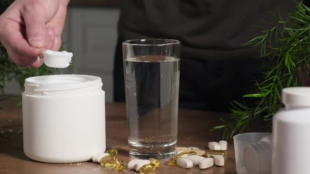 A man dissolves some of the creatine or amino acids in water, close-up. Concept: sports nutrition, bodybuilding, fitness