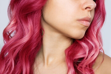 Close-up of the wavy hot pink hair of a young woman isolated on a white background. Result of coloring, highlighting, perming. Bright saturated extravagant color. Beauty and fashion