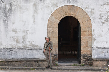Fototapeta na wymiar Pilgrim with hat, bag and cane in Church on the Camino de Santiago. Way of St James