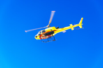 A yellow helicopter flying up in the air