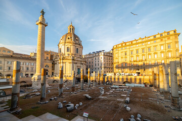 Obraz premium Ruins of Roman forum with Trajan column and church of the Most Holy Name of Mary. Rome cityscape on sunset. Concept of historical landmarks and travel Italy