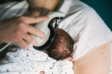 Crop mom checking hearing of infant in hospital