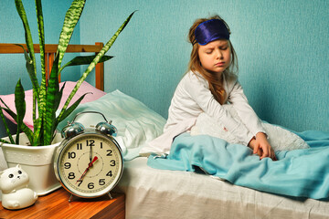 Dissatisfied upset child girl schoolgirl in white pajamas woke up early in the morning, does not...