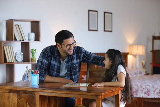 Indian Father And Her Young Daughter - Studying At Home, Doing School Home Work. Smiling Father And Smiling Daughter - Single Indian Male With Her Small Girl. Happy Family, Parenting, Love And Care