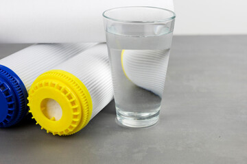 A glass of clean water next to the water purification filter. The concept of a household filtration...