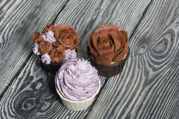 Cupcakes with cream and mascarpone. On pine boards. Close-up.