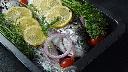 Fresh trout on a table with lemon, pepper and dill. Tasty fish ready for cooking. Healthy seafood and dieting concept.