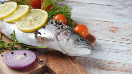 Fresh trout on a table with lemon, pepper and dill. Tasty fish ready for cooking. Healthy seafood and dieting concept.