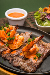Grilled flank steak with shrimp with red sauce and parsley