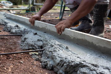 Worker's hands distributing cement on the floor. Construction 