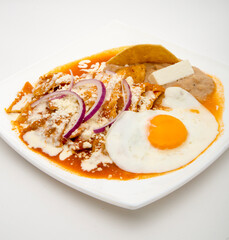 Mexican breakfast of red chilaquiles with egg and purple onion