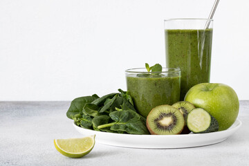 Green smoothie in glasses on white background, copy space. Selective focus. Green detox smoothie of spinach, kiwi, apple, cucumber and lime in glasses on a white background.