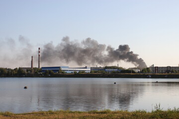 Fototapeta premium Factory atmosphere pollution black acrid smoke rises into the sky above the ground