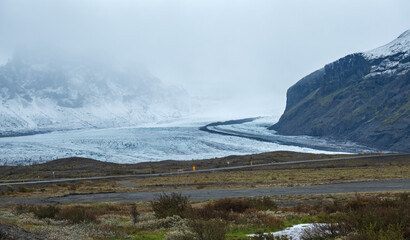 View from highway road during auto trip in Iceland. Spectacular Icelandic landscape with  scenic nature: hamlets, mountains, ocean coast, fjords, fields, clouds, glaciers, waterfalls.