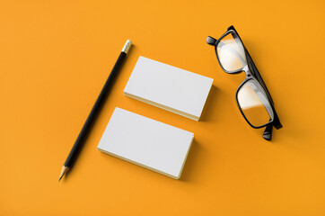 Photo of blank stationery set. Business cards, glasses and pencil on yellow background.
