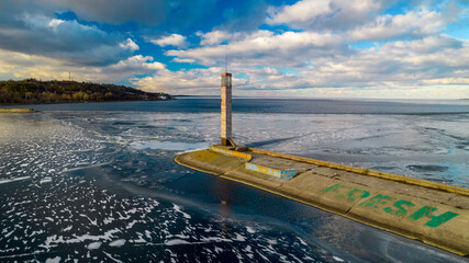 Aerial view of a pier with a lighthouse on a frozen lake
