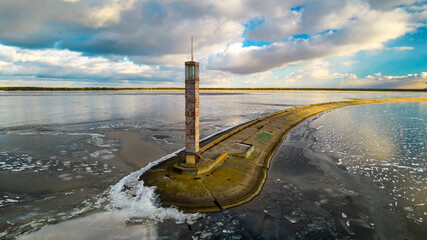 Aerial view of a pier with a lighthouse on a frozen lake