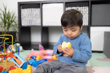 two years old mexican baby boy eating guayaba on messy room