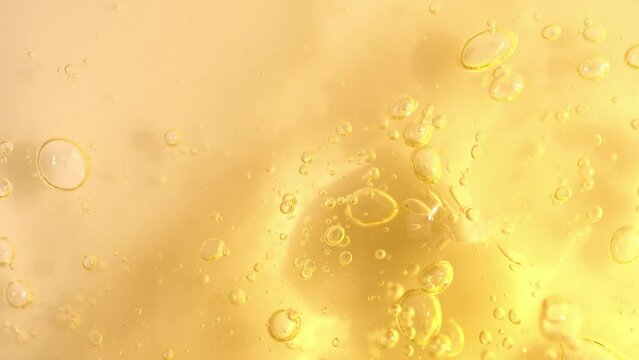 Vitamin C serum texture with slowly moving bubbles, orange cosmetics gel, macro shot.