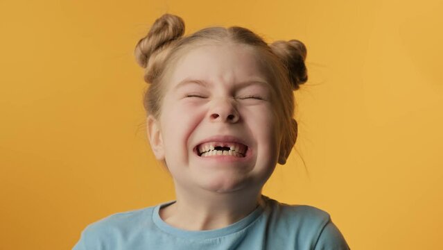 Portrait of little girl with toothless smile at yellow background. Child having fun. Cheerful child expressing positive emotions. 4K, UHD