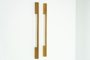 Furniture handles on white wardrobe for bedroom.  Furniture fittings from natural oak wood in modern eco style.
