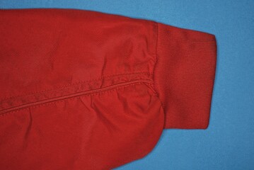 one red sleeve of a shirt made of synthetic fabric with lies on a blue table