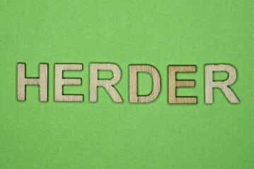 gray word herder from small wooden letters on a green table