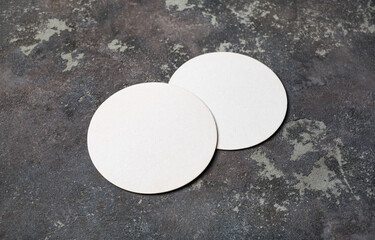 Photo of two blank white beer coasters on concrete background. Blank template for your design.