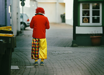 Einsamer Clown. Ein Mensch von hinten in Karnevalskostüm. 