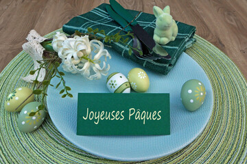 Table de Pâques dressée avec le mot Joyeuses Pâques écrit sur une carte.