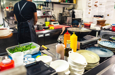 Professional chef cooking in the kitchen restaurant at the hotel, preparing dinner. A cook in an apron makes a salad of vegetables and pizza.