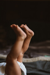 little girl lies on the bed and raised her legs up