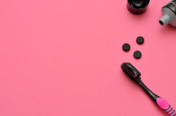 black toothpaste with activated charcoal on pink background, copy space