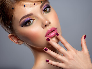 Portrait of a beautiful woman with bright makeup. Closeup female face with purple eye make-up....