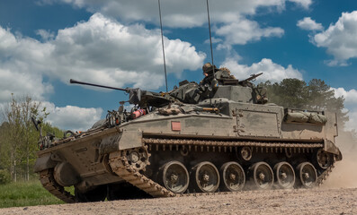 detailed close-up of a British army Warrior FV510 light infantry fighting vehicle tank in action on a military exercise, blue sky with light clouds, Wiltshire UK