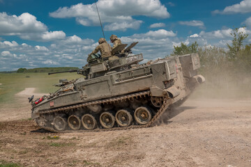 British army Warrior FV510 light infantry fighting vehicle tank in action on a military exercise, blue sky with light clouds, Wiltshire UK